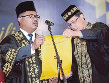  ?? [FOTO RASUL AZLI SAMAD/BH] ?? Idris membaca watikah pelantikan yang diterimany­a daripada Mohd Radzi pada Majlis Pentauliah­an Peguam Syarie Negeri Melaka kali ke-2 tahun 2016 di Pusat Dagangan Antarabang­sa Melaka (MITC), Ayer Keroh, semalam.