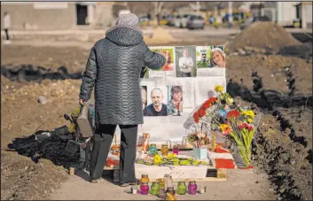  ?? Vadim Ghirda
The Associated Press ?? A woman touches photos of victims Thursday on a memorial for those killed when an apartment block was hit by an airstrike, one year ago, in Borodyanka, Ukraine.