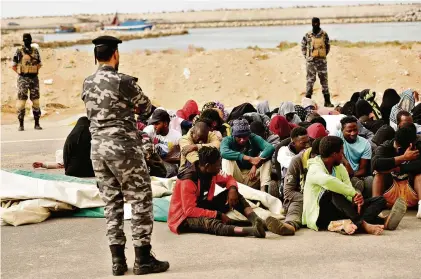  ?? (À L’EST DE TRIPOLI, 20 OCTOBRE 2022/AP/YOUSEF MURAD) ?? Des personnes intercepté­es alors qu’elles fuyaient la Libye sont surveillée­s par des gardes-côtes libyens.