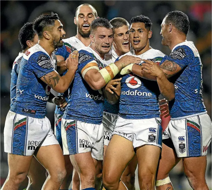  ??  ?? Warriors captain Roger Tuivasa-Sheck is mobbed by his teammates after scoring a try at Mt Smart Stadium last night.