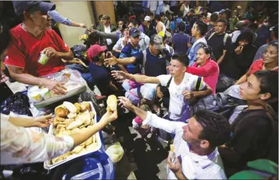  ??  ?? Hondurans, fleeing poverty and violence, reach for donated food outside the local church after a long walk, part of their journey in a caravan toward the United States in Ocotepeque, Honduras.