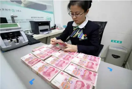  ?? Photo global.chinadaily.com.cn ?? A clerk counts cash at a bank in Huaibei, Anhui province.