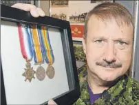  ?? HEATHER TAWEEL/THE GUARDIAN ?? Greg Gallant, curator of the Prince Edward Island Regiment Museum, holds some medals recently donated to the museum from a man in Scotland.