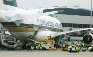  ?? (Tim Wimborne/Reuters) ?? AIRPORT WORKERS at Sydney Internatio­nal Airport crowd around the first scheduled commercial flight of an Airbus A380, after flying from Singapore in 2007.