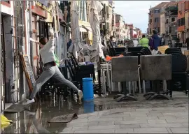  ?? ANDREA MEROLA — ANSA VIA AP ?? A woman jumps over a puddle during cleanup following a flooding in Venice, Italy. It is the worst flooding in Venice in more than 50 years.