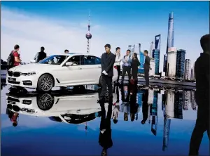  ?? AP file photo ?? Visitors check out a BMW vehicle at last year’s Shanghai auto show. China says it plans to work to make it easier over the next five years for foreign automakers to own factories in that country.