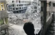  ?? AMMAR SULEIMAN / AFP / GETTY IMAGES ?? A Syrian youth surveys airstrike damage in Eastern Ghouta on the outskirts of Damascus on Friday.