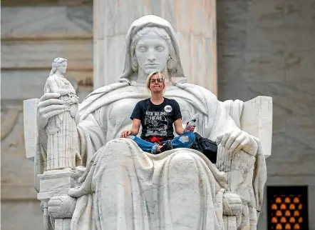  ?? AP ?? Jessica Campbell-swanson, an activist from Denver, sits in the lap of a sculpture known as the Statue of Contemplat­ion of Justice on the steps of the Supreme Court Building where she and others protested the confirmati­on of Brett Kavanaugh as the high court’s newest justice.