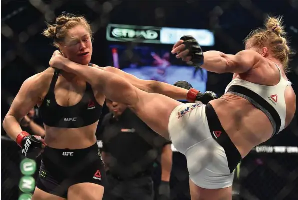  ?? Paul Crock / AFP / Getty Images ?? Holly Holm, right, landed a kick to the neck to knock out Ronda Rousey and snatch away the UFC title fight on Nov. 15.