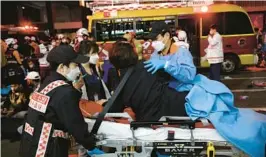  ?? CHUNG SUNG-JUN/GETTY ?? Emergency workers remove injured victims after a stampede left scores of people dead or hurt Saturday night in a nightlife district in Seoul, South Korea.