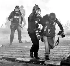  ??  ?? Photo journalist­s and video journalist­s wearing gas masks flee from tear gas during clashes with Israeli forces near an Israeli checkpoint in the West Bank city of Ramallah. — AFP photo