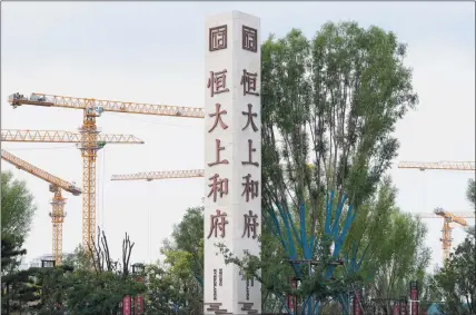  ?? Associated Press ?? Constructi­on cranes stand near the Evergrande’s name and logo at its new housing developmen­t in Beijing on Wednesday. One of China’s biggest real estate developers is struggling to avoid defaulting on billions of dollars of debt, prompting concern about the broader economic impact and protests by apartment buyers about delays in completing projects.