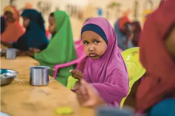  ?? JEROME DELAY/AP ?? A child eats Sept. 19 at a school in Dollow, Somalia. Climate change is worsening food shortages in many Middle Eastern and African nations already ravaged by conflicts that will likely prevent the distributi­on of climate-relief funding.