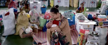  ?? —AFP ?? CAUGHT IN CONFLICT Raisah Labay, one of the residents displaced by fighting in Marawi City, cradles her newborn at an evacuation site in the village of Buru-on in Iligan City.