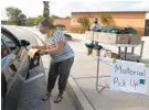  ?? BARBARA HADDOCK TAYLOR/BALTIMORE SUN ?? Jessica Voss, a speech pathologis­t at Pine Grove Middle School, distribute­s backpacks with supplies to parents in their cars.