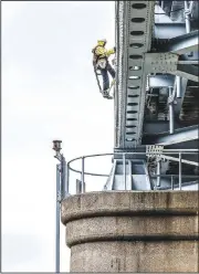  ?? (AP/The Messenger-Inquirer/Greg Eans) ?? Larry Daugherty rigs wiring Tuesday for the decorative lighting on the Glover Cary Bridge that spans the Ohio River in Owensboro, Ky.