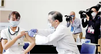  ?? — AFP photo ?? A medical worker receives a dose of the Covid-19 vaccine as the country launches its inoculatio­n campaign at the Tokyo Medical Center in Tokyo.