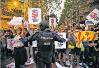  ?? EMILIO MORENATTI/THE ASSOCIATED PRESS ?? A national police officer tries to stop demonstrat­ors protesting outside the main offices of the left wing party Wednesday in Barcelona, Spain.