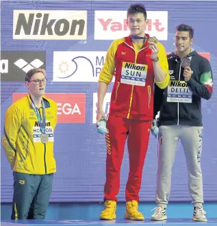  ??  ?? China’s Sun Yang, centre, holds up his 400m freestyle gold medal as runner-up Mack Horton of Australia, left, stands away from the podium.