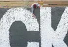  ??  ?? Artist Shannan Fleet of Westervill­e paints in letters on the large mural in the Milo-grogan neighborho­od of Columbus on Sunday.