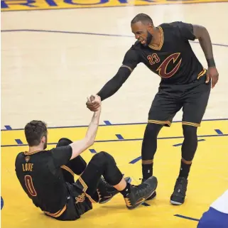  ??  ?? CARY EDMONDSON, USA TODAY SPORTS LeBron James, helping up teammate Kevin Love, says his Cavaliers will try to find a way to get on track in the NBA Finals against the Warriors, who have dominated the series.