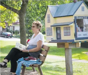  ?? VINCENZO D’ALTO ?? Carole Thériault sits by Beacon Hill Park’s new miniature library. Users are encouraged to take and leave books for others.