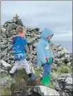  ??  ?? From left: Youngsters from Gigha Primary School make it to the first of three cairns; participan­ts walked and scooted throughout the challenge; and the three-peaks challenge gets a thumbs up from this pupil standing at the second cairn.