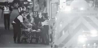  ??  ?? Emergency workers attend to a person injured in an apparent terror attack in London on Saturday night. The attack left six people dead and 30 injured. Daniel Sorabji, Afp/getty Images