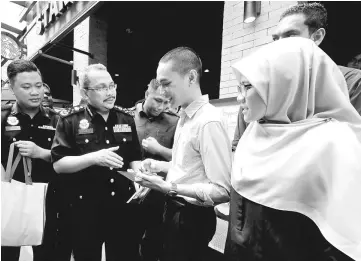  ??  ?? Dzulkifli (second left) handing out brochure to the public after he attended the ‘Friends of MACC’ event. — Bernama photo