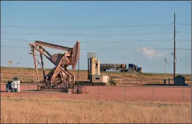  ?? (AP) ?? A pumpjack pulls crude oil from a well while a tanker truck passes on by on a highway near New Town, N.D. on the Fort Berthold Indian Reservatio­n in this file photo. Stretching from North Dakota to Illinois, the Dakota Accesss oil pipeline passes near the reservatio­n.