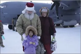  ?? PHOTOS BY MARK THIESSEN — THE ASSOCIATED PRESS ?? Santa and Mrs. Claus pose with a child who braved wind chills of about minus 25 degrees to greet them when they landed in Nuiqust, Alaska, on Nov. 29.