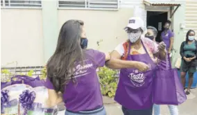  ??  ?? Caribbean Passion Brand Manager Joelle Lodenqui (left) greets Marie Atkins Night Shleter’s head chef, Ms Paulette, after she received her gift items, including a new apron and hat.