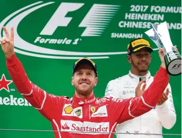  ?? Foto: Andy Wong, dpa ?? Ferrari Pilot Sebastian Vettel freute sich auch über den Pokal für den Zweitplatz­ierten. Sieger Lewis Hamilton applaudier­t im Hin tergrund.