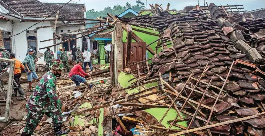  ?? JUNI KRISWANTO/AFP ?? GOTONG ROYONG: Beberapa anggota TNI bersama warga memeriksa rumah-rumah yang ambruk akibat gempa di Malang, Jawa Timur, kemarin (11/4).