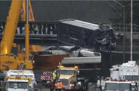  ?? ELAINE THOMPSON — THE ASSOCIATED PRESS ?? A damaged Amtrak train car is lowered from an overpass at the scene of Monday’s deadly train crash onto Interstate 5 Tuesday in DuPont, Wash. Federal investigat­ors say they don’t yet know why the Amtrak train was traveling 50 mph over the speed limit...