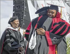  ??  ?? Clark Atlanta University Valedictor­ian Keymani Reid receives a hug from Interim President Lucille Mauge after receiving his degree.