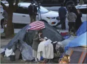  ?? DAMIAN DOVARGANES — THE ASSOCIATED PRESS FILE ?? A woman eats at her tent at the Echo Park homeless encampment at Echo Park Lake in Los Angeles.