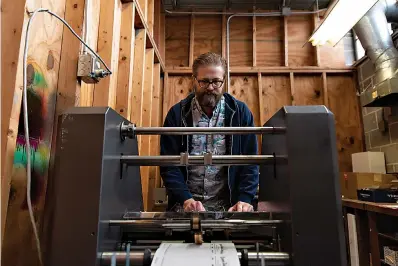  ?? Staff photo by Kelsi Brinkmeyer ?? ■ Jacob Cuthbertso­n, production manager at Digital Press, operates a press on Thursday at the store’s new location, 2121 N. State Line Ave., which was formerly The Vintage Bucket.