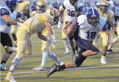  ?? GREG SORBER/JOURNAL ?? Manzano quarterbac­k Michael Roybal (18) leaps across the goal line after Atrisco Heritage’s Angel Ramirez hit him.