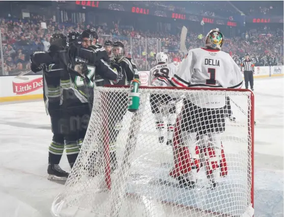  ?? ROSS DETTMAN/ WOLVES ?? The short-handed Wolves celebrate one of their five goals during the victory Sunday against the IceHogs at Allstate Arena.