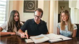  ?? KRISTINA WINDSOR/ SUN- TIMES ?? Retired Navy Cmdr. John Capizzi pores over his GI Bill records with daughters Raegan ( left), 14, and Cambria, 16. He fought the VA successful­ly to be able to use his benefits to pay for college for them.