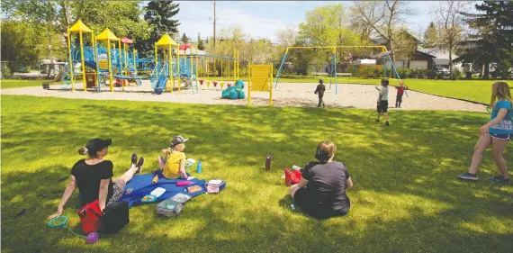  ?? GAVIN YOUNG ?? Children play in the park next to a closed playground in Bridgeland on Thursday. The city is starting the process to reopen playground­s Friday, but must inspect each one first.