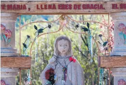  ??  ?? A statue behind El Santuario de Chimayó, where people often leave rosaries and devotional images.