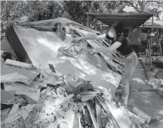  ?? Charlie Riedel / Associated Press ?? Lucy Liu dumps trash on a pile of debris as she helps her co-worker Tianna Oliver clean out her flood-damaged house.