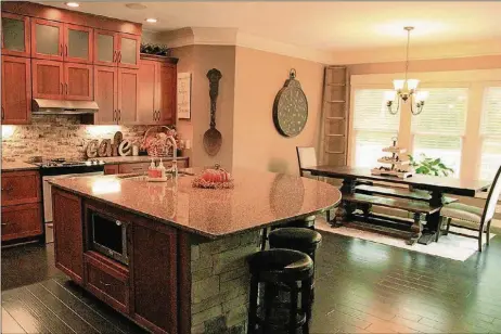  ?? KATHY TYLER CONTRIBUTE­D PHOTOS BY ?? An oversized island with quartz countertop is the focal point of the kitchen and breakfast room.