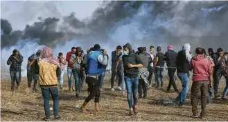  ?? Adel Hana / Associated Press ?? Palestinia­n protesters run to cover from teargas Friday during clashes with Israeli troops along Gaza’s border with Israel, where demonstrat­ors sought to dismantle the border fence.