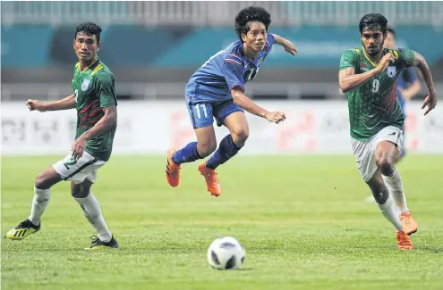  ??  ?? Thailand midfielder Thanasit Siriphala, centre, is tripped by a Bangladesh player on Friday.