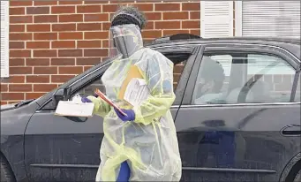  ??  ?? A health care worker gathers paperwork from a driver at the drive-through COVID-19 testing site at the Whitney Young Administra­tive Building on Wednesday in Watervliet.