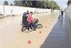  ?? — AFP ?? A motorcycli­st rides in the flooded water in the Tunisian coastal governorat­e of Nabeul on Sunday following deadly flash flooding.