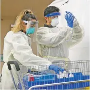  ?? MATT DAHLSEID/NEW MEXICAN FILE PHOTO ?? Health care workers at Presbyteri­an Santa Fe Medical Center’s COVID-19 drive-up testing site check their equipment before beginning testing earlier this year. Presbyteri­an is one of three health providers halting testing for people who are asymptomat­ic, but it will continue to test people exposed to someone with a known COVID-19 infection.